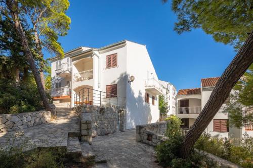 an exterior view of a white house with trees at Lavica Seaside Apartments, Podstrana in Podstrana