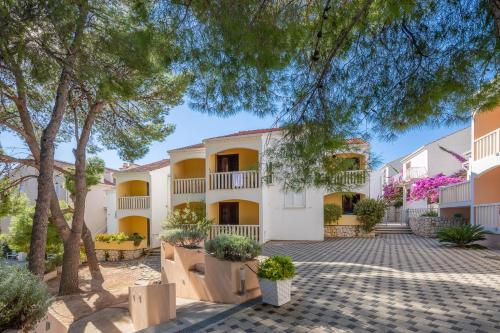 a large white building with trees in front of it at Lavica Seaside Apartments, Podstrana in Podstrana