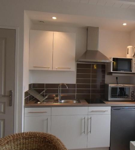 une cuisine avec des armoires blanches, un évier et un micro-ondes dans l'établissement Lesneven Appart Nuitee, à Lesneven