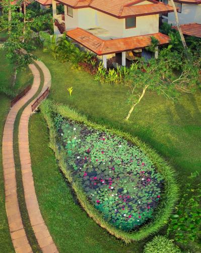 a garden with flowers in the grass next to a house at Niraamaya Wellness Retreats Backwaters And Beyond Kumarakom in Kumarakom