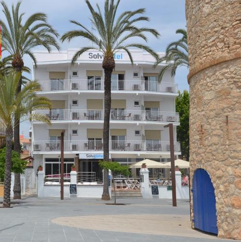 a hotel with palm trees in front of it at Solvi Hotel - Adults Only in Vilanova i la Geltrú