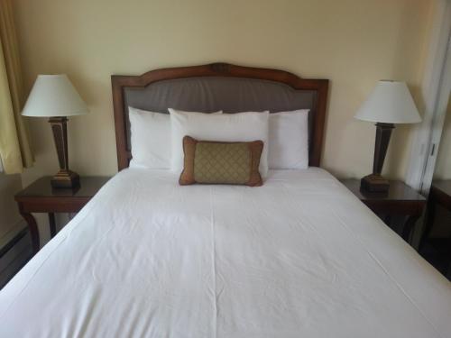 a bed in a hotel room with two lamps at The Vendange Carmel Inn & Suites in Carmel