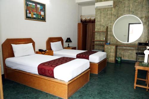 a hotel room with two beds and a mirror at Fiesta Inn Hotel & Resorts Multan in Multan
