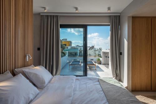 Hub Suites, Luxury living in Athens في أثينا: غرفة نوم بسرير وشرفة مطلة