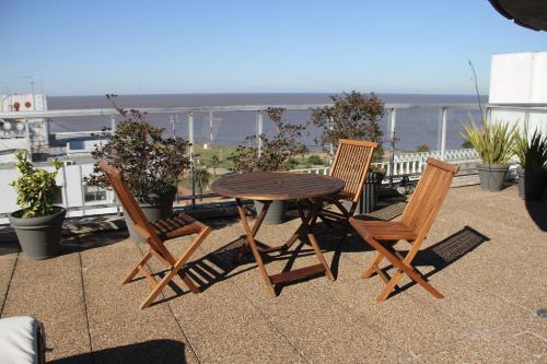 a wooden table and chairs on a balcony with the ocean at Punta Trouville Hotel in Montevideo
