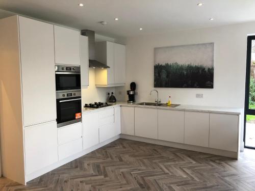 a kitchen with white cabinets and a sink at Killester Self Catering Cottage in Dublin