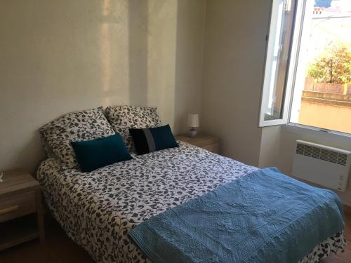 - une chambre avec un lit doté de draps bleus et une fenêtre dans l'établissement Coeur de village, à Bormes-les-Mimosas
