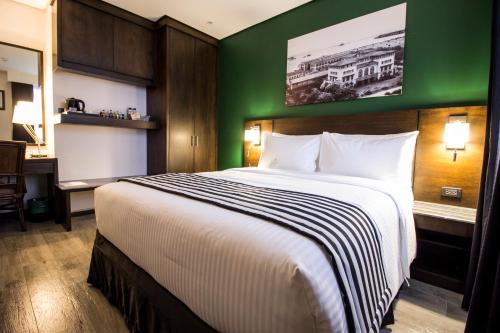 a bedroom with a large bed with a green wall at 1898 Hotel Colonia En Las Filipinas in Manila