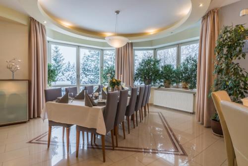 a dining room with a table and chairs and windows at Rezydencja Marjo z basenem in Kościelisko