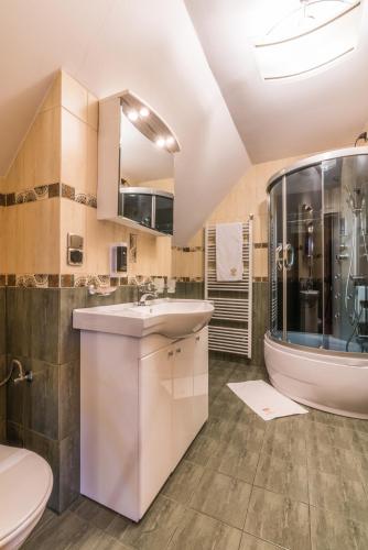 a bathroom with a sink and a toilet and a tub at Rezydencja Marjo z basenem in Kościelisko