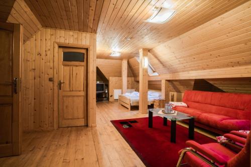 a living room with a red couch and a bed at Rezydencja Marjo z basenem in Kościelisko