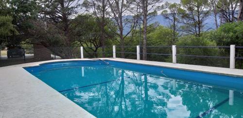 una piscina azul con una valla y árboles en La Alegria en Nono