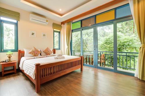 a bedroom with a bed and a balcony with windows at Baan Patcharintorn Samui in Chaweng