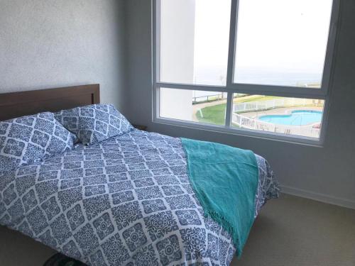 a bedroom with a bed with a view of a pool at Costa Quilén - Vista al Mar Dpto 241 in Puchuncaví