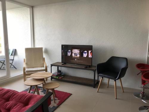 sala de estar con TV y algunas sillas en Costa Quilén - Vista al Mar Dpto 241 en Puchuncaví