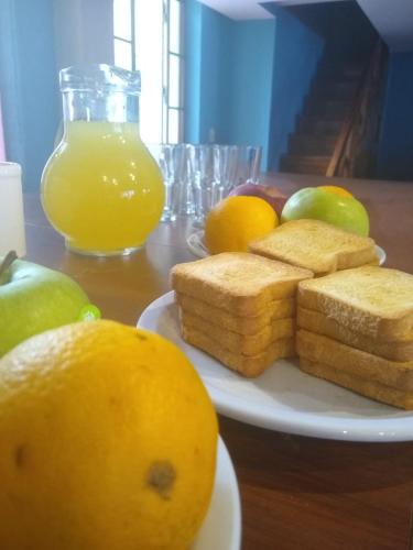 een bord met brood en fruit op tafel met sinaasappelsap bij Black Sheep International Hostel in Mendoza