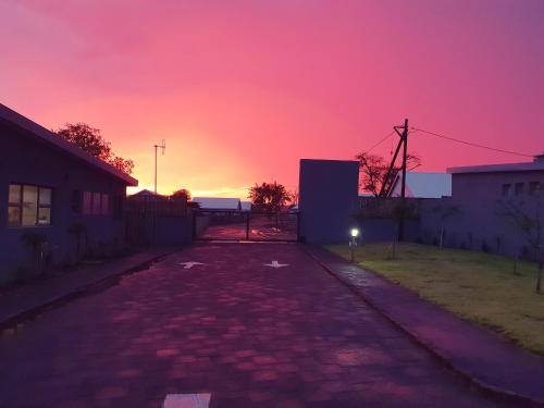 an empty street with a sunset in the background at Sandpiper Villas Chobe in Kasane