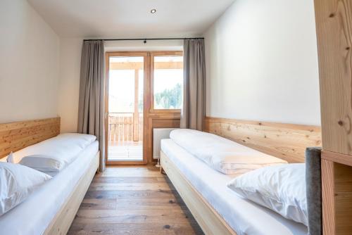two beds in a room with a window at Hotel Trattlerhof in Bad Kleinkirchheim