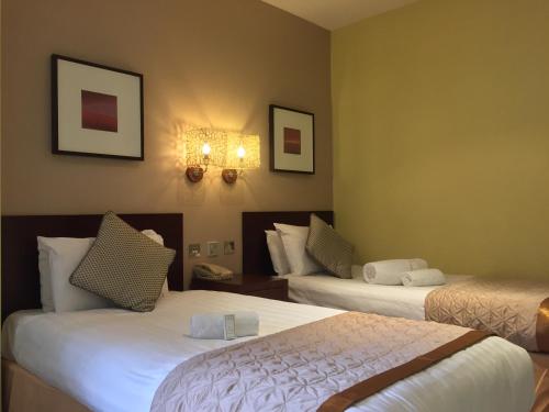 a hotel room with two beds and two lights on the wall at Brook Mollington Banastre Hotel & Spa in Chester