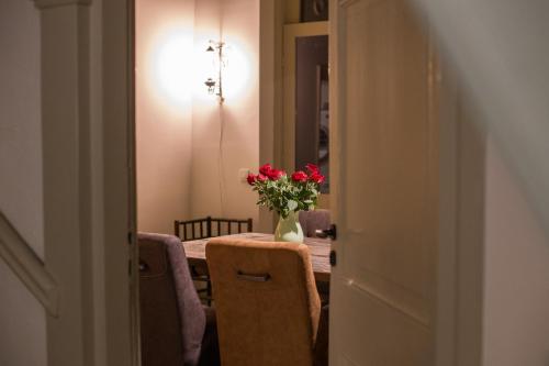 a dining room with a table with a vase of flowers at Bed & Breakfast Huis Sevenaer in Zevenaar