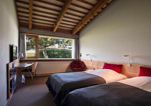 a room with two beds and a desk and a window at Konventum Conference Center in Helsingør