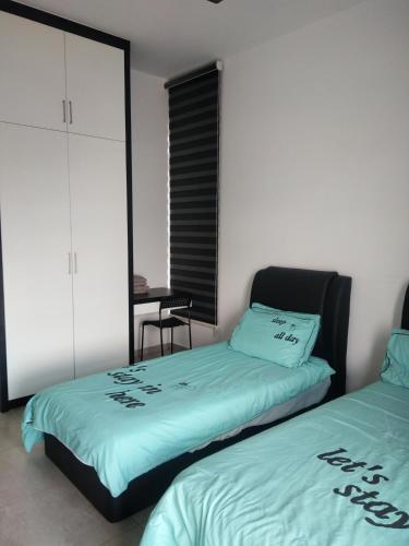 a bedroom with two beds and a table with a chair at Atlantis Residence Melaka in Melaka