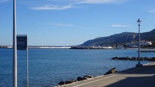 a large body of water with a sign on the sidewalk at ARETOUSA in Agia Pelagia Kythira