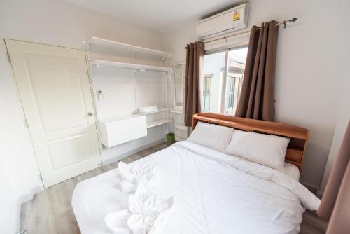 a bedroom with a white bed and a window at Munlihouse Cha-Am Hua-Hin Beach in Cha Am