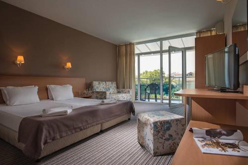 a hotel room with a bed and a flat screen tv at Hotel Eskada Beach in Ahtopol