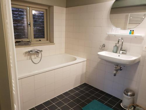a bathroom with a bath tub and a sink at Bed & Breakfast Huis Sevenaer in Zevenaar