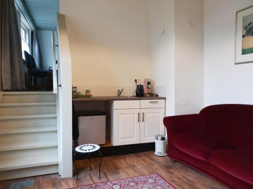 a living room with a red couch and a kitchen at Bed & Breakfast Huis Sevenaer in Zevenaar