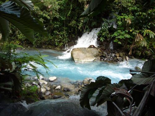 a river with a waterfall surrounded by rocks and trees at Blue River Resort & Hot Springs in Liberia