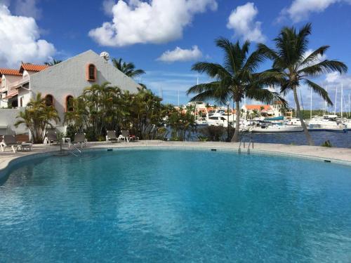 a large swimming pool with palm trees and a house at Simpson Bay Yatch Club 2 Bedrooms in Simpson Bay