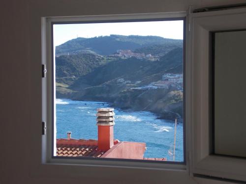 a window with a view of the ocean and a lighthouse at Bellagio in Castelsardo