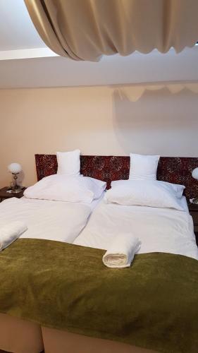 two beds with white sheets and a green blanket at Tarnóca Kúria in Soponya