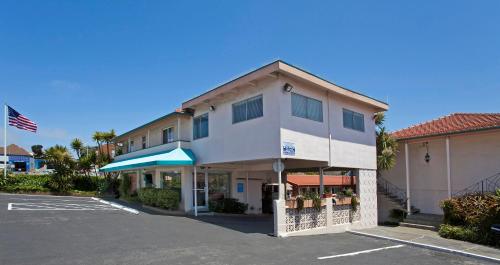 a building in front of a parking lot at El Camino Inn in Daly City