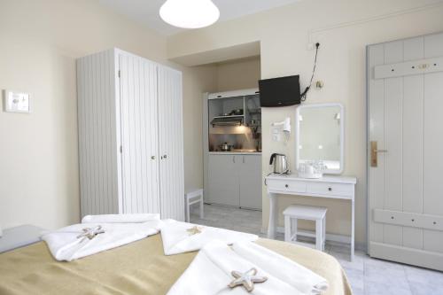 a white bedroom with a bed and a desk at Alexandra's Rooms in Parikia