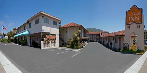 an empty street in a small town with buildings at El Camino Inn in Daly City