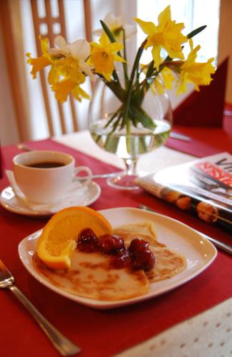 a plate of food with fruit on a table with a cup of coffee at City Gate in Vilnius