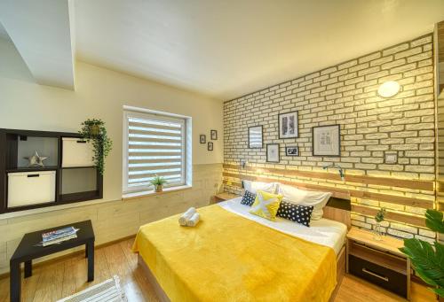 a bedroom with a yellow bed and a brick wall at Fox Rooms Aparthotel in Stara Zagora