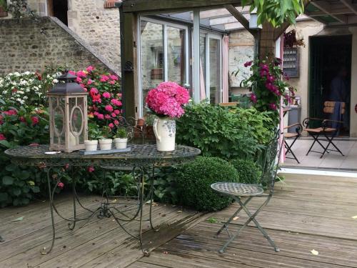 - une table avec des fleurs et une lanterne sur la terrasse dans l'établissement Chambres d'Hôtes Côté Campagne, à Vaux-sur-Aure