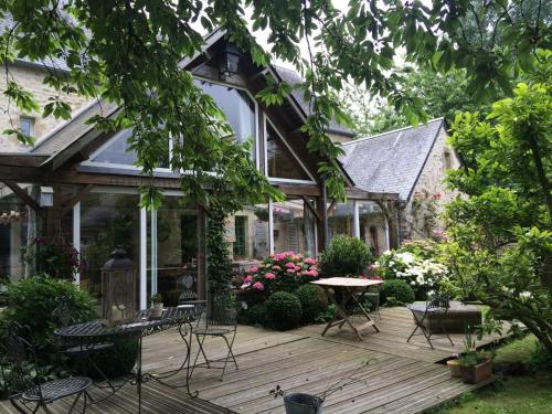 a house with a wooden deck with a table and chairs at Chambres d'Hôtes Côté Campagne in Vaux-sur-Aure