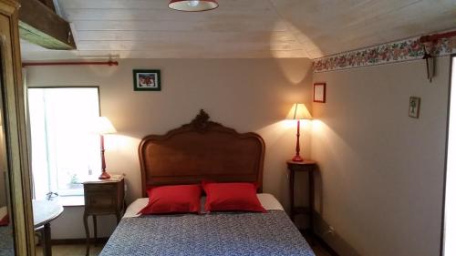 a bedroom with a bed with two red pillows at Chambres d'Hôtes Côté Campagne in Vaux-sur-Aure