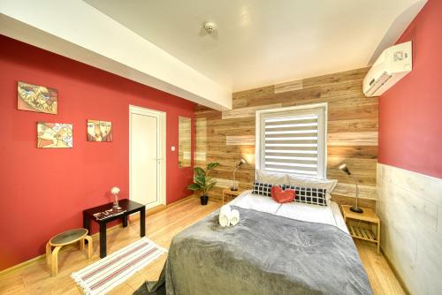 a bedroom with a bed and a red wall at Fox Rooms Aparthotel in Stara Zagora