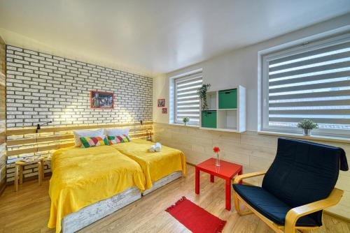a bedroom with a yellow bed and a chair at Fox Rooms Aparthotel in Stara Zagora