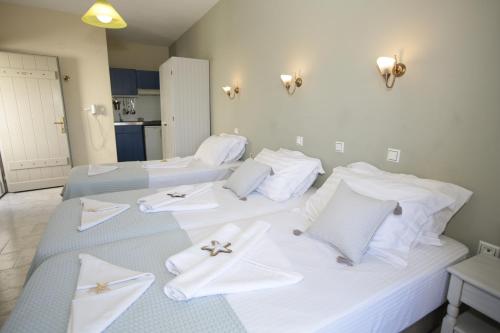 two beds in a room with white towels on them at Alexandra's Rooms in Parikia