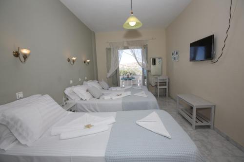 a bedroom with two beds and a tv and a television at Alexandra's Rooms in Parikia