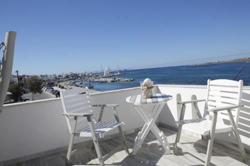 two chairs and a table on a balcony overlooking the water at Alexandra's Rooms in Parikia