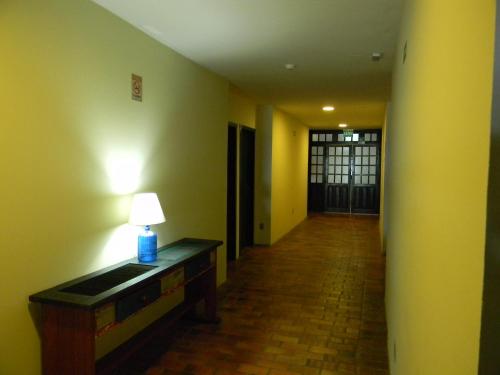 a hallway with a table with a lamp on it at Pousada Recanto da Prainha in Torres