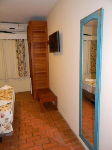 a mirror in a room with a room with a bed at Pousada Recanto da Prainha in Torres